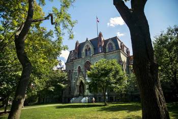 Photo showing the exterior of the University of Pennsylvania. The building looks like a castle and is surrounded by trees